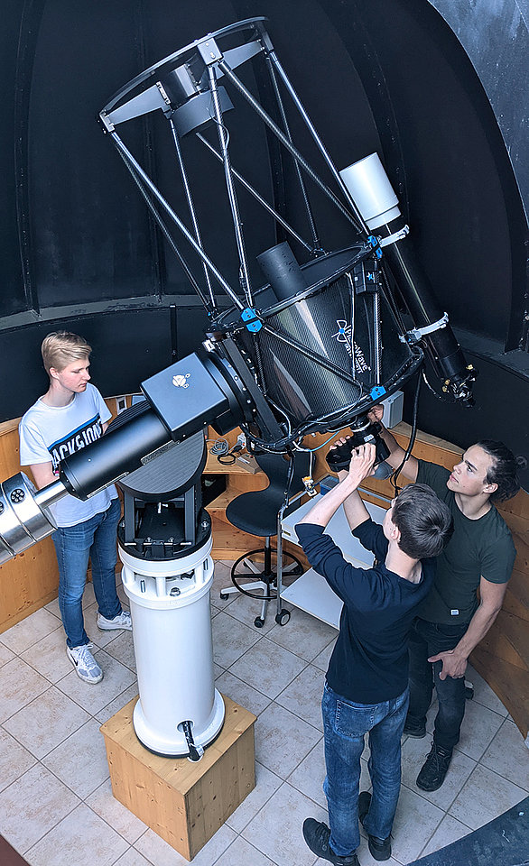 Schüler montieren die astronomische Kamera am Teleskop im Kuppelraum.