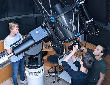 Schüler montieren die astronomische Kamera am Teleskop im Kuppelraum.